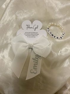 a white bow with a name tag on it and a bracelet that reads, thank god