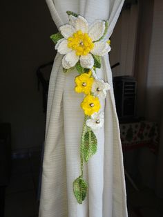 a white dress with yellow flowers and green leaves on the waist, draped by a curtain