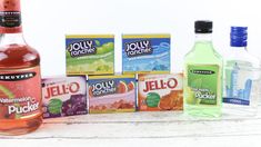 bottles of jello and other drinks on a white wooden table next to each other