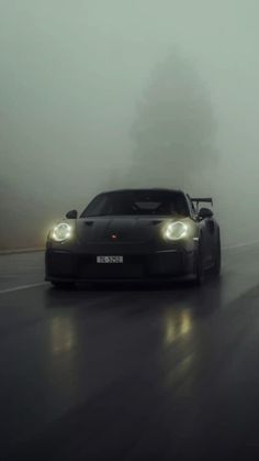 a black sports car driving on a foggy road