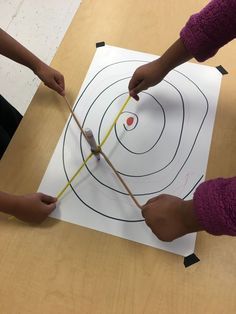 two children are using sticks to draw a target on the paper that they are holding in their hands