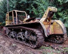 an old bulldozer sitting in the middle of a forest