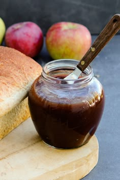 a jar of peanut butter next to some apples and bread