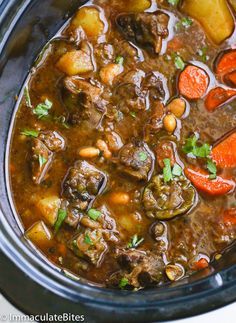 a crock pot filled with beef stew and carrots