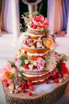 the cake is decorated with flowers and hearts on it's tiered stand,