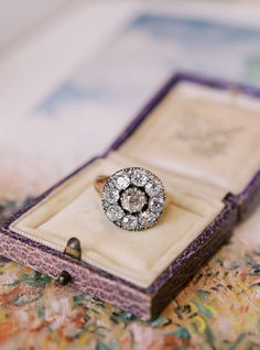 a diamond ring sitting in a box on top of a floral print table cloth,