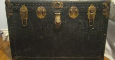 an old black suitcase sitting on top of a hard wood floor