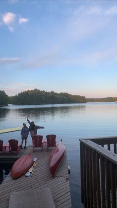 two people standing on a dock next to canoes