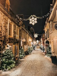 a street with christmas lights and decorations on the side of it, at night in an old european town