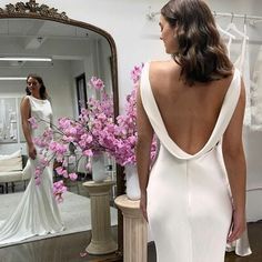 a woman standing in front of a mirror wearing a white dress