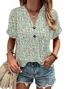 a woman wearing shorts and a floral shirt with fringes on the sides, holding a purse