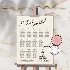 a wedding seating chart on a easel with a pink pom - pom