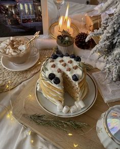 a cake with blueberries and cream is on a plate next to a lit candle