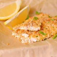 two pieces of fried fish with lemon wedges