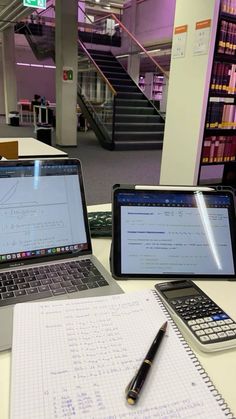 two laptops and a calculator are sitting on a table in an office