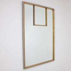 a mirror hanging on the wall next to a white wall with gold trimmings