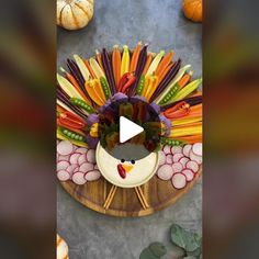 a turkey made out of vegetables on top of a wooden platter next to pumpkins