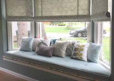 a window seat with many pillows on it