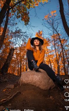 a woman sitting on top of a rock in the woods