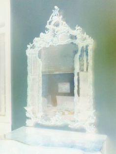 an ornate white mirror sitting on top of a dresser