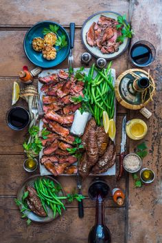 an assortment of meats and vegetables on a wooden table