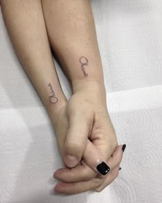 two people holding hands with tattoos on them