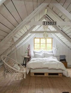 an attic bedroom with white walls and wood flooring, a hammock hanging from the ceiling