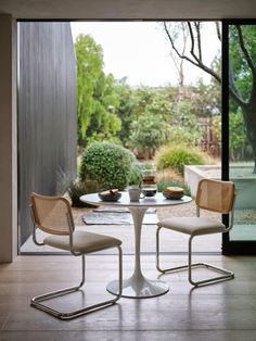 two chairs sitting at a table in front of a glass door with an outside view