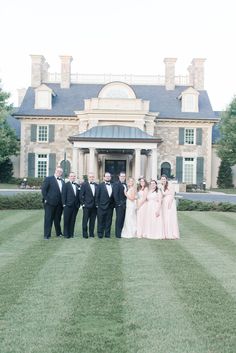 a group of people standing in front of a large building on top of a lush green field