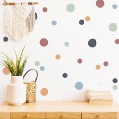 a white wall with multicolored polka dot decals next to a potted plant