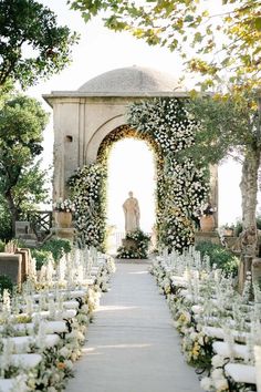 an outdoor ceremony setup with white flowers and greenery on the aisle, surrounded by trees