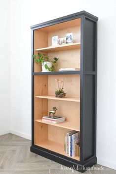 a book shelf with books and plants in it on the floor next to a wall