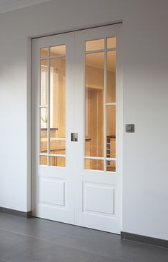 an empty room with two white doors and no one sitting in the chair next to it