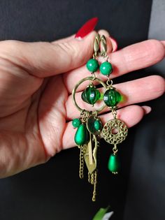 Beautiful handmade earrings with deep green dyed marble beads and lamwork glass beads. The rest of the elements are in bronze brass which gives it a slightly vintage look. These earrings are the fruit of my imagination, they are asymmetrical, different from each other but in the same style. This design is very current today, having two different earrings is very intriguing. The earrings are long with a closure on the back. The earrings are very particular, they have a vintage look but at the same time they are very elegant. For those who love handmade jewellery. All jewels are delivered in a decorated box, ready to be given as a gift to your loved one. How to take care of your jewellery: put on your beauty products (cosmetics, perfumes, ...) before wearing your precious jewel. Clean your j Artistic Green Jewelry With Matching Earrings, Green Metal Beaded Earrings With Round Beads, Green Beaded Earrings With Round Metal Beads, Vintage Green Beaded Earrings, Vintage Dangle Earrings With Colorful Beads, Vintage Green Beaded Earrings With Round Beads, Green Metal Round Bead Earrings, Unique Green Earrings With Colorful Beads, Green Brass Earrings With Round Beads