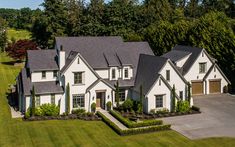 an aerial view of a large white house in the middle of a lush green field