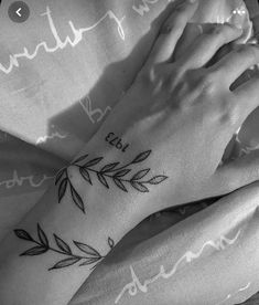 two hands holding each other with tattoos on them