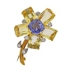 18k gold flower brooch by Cartier, set with approx. 0.85ctw in diamonds, center blue sapphire - approx. 5.50ct, and four yellow sapphire petals, each approx. 6 - 6.50cts. The brooch is 46mm x 32mm. Marked Cartier. Weighs 17.7 grams. SKU#PB-03022 Luxury Elegant Cartier Brooches, Luxury Cartier Elegant Brooches, Luxury Mid-century Brooch Jewelry, Luxury Blue Diamond Brooches, Luxury Blue Fine Jewelry Brooches, Luxury Gold Brooch With 17 Jewels, Luxury Elegant Sapphire Brooch, Luxury Blue Sapphire Brooch, Luxury Antique Blue Brooches