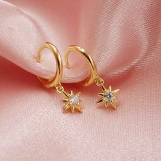 The cutest pair of huggie hoops glisten with a tiny dangling star. Available in gold or silver. Each star is adorned with a sparkly cz stone for some extra shine! Wear these in a first, second or third piercing to create a beautiful celestial ear stack. DETAILS - 14kt gold plated or sterling silver - cubic zirconia inlay - 12mm across Packaging + Delivery: All items come packaged in a cute Amanda Deer Jewelry box and are sent in a protective bubble mailer. If ordering multiple pieces, please let Gold Sparkling Huggie Earrings For Gift, Gold Star Charm Hoop Earrings, Celestial Huggie Earrings With Star Charm Dangle, Celestial Dangle Huggie Earrings With Star Charm, Gold Dainty Huggie Earrings With Star Charm, Celestial Star Huggie Earrings, Gold Huggie Hoop Earrings With Star Charm, Dainty Gold Star Huggie Earrings, Star-shaped Hoop Earrings With Dangling Charms For Gift