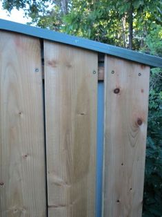 a close up of a wooden fence with trees in the background