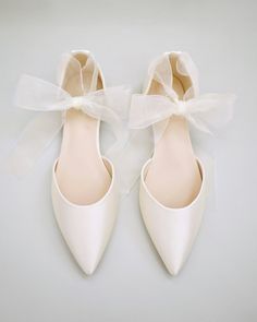 a pair of white shoes with bows on them