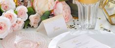 the table is set with pink flowers and white plates, silverware, and champagne