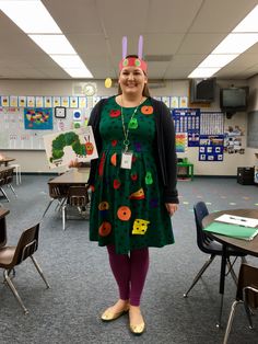 a woman standing in a classroom wearing a green dress with buttons on it's head