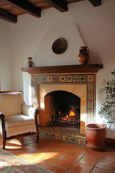 a living room with a fireplace, chair and potted plant