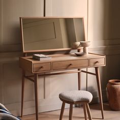 a wooden dressing table with mirror and stool