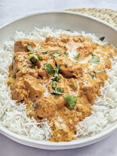 a white bowl filled with rice and meat covered in cilantro sauce, garnished with parsley