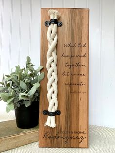 a wooden plaque with a white rope on it and a potted plant next to it