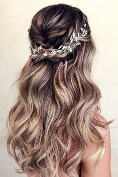 the back of a woman's head with long wavy hair and flowers in her hair