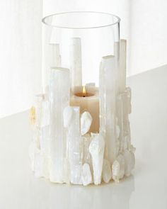 a candle that is sitting in some kind of glass holder with rocks and crystals around it