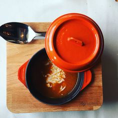 two bowls of soup on a cutting board with spoons