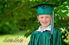 a young boy wearing a green graduation cap and gown